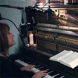 Julie singing at a piano.